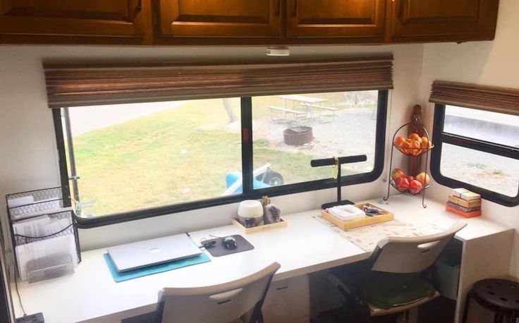 a desk with two chairs in front of a large window that looks out onto a grassy field