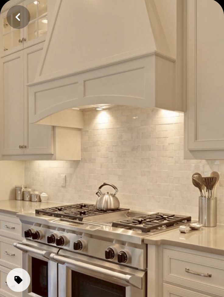 a stove top oven sitting inside of a kitchen next to white cabinets and counter tops