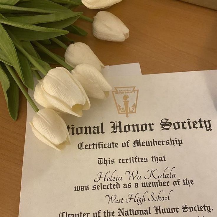 a diploma with flowers on top of it and some papers in front of the paper