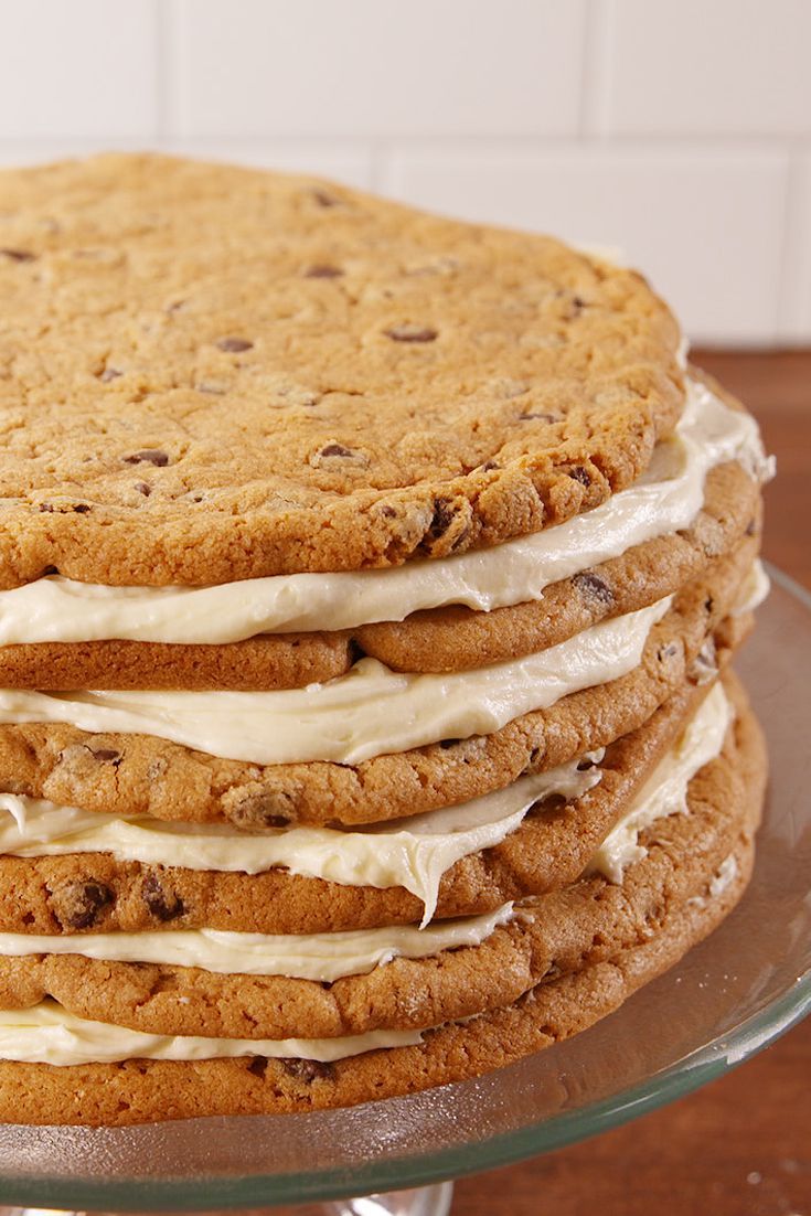 a stack of cookies sitting on top of a glass cake plate covered in frosting