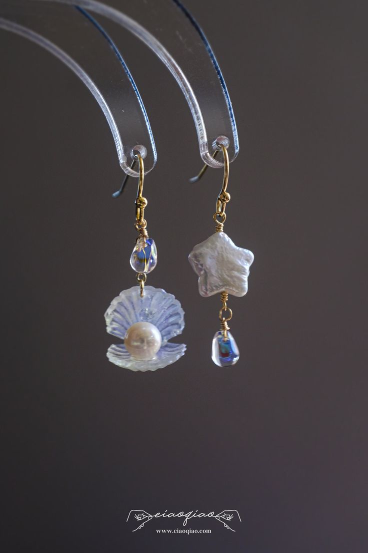 ---- Welcome to CiaoQiao Shop ----- These stunning, sea-inspired dangle earrings crafted with delicate care, each earring features a shimmering pearl nestled in a lustrous shell, complemented by a cascade of blue crystal droplets that reflect the tranquil hues of the sea. The iridescent glow of the shells and pearls brings a natural, serene beauty to any ensemble. Perfect for beach weddings, seaside events, or adding a splash of oceanic charm to your everyday wear. Length including hooks: 1 1/2" | 3.8cm Please note: natural pearls will have flaws and each is unique. Tips for making your Jewelry last longer - Remove your jewelry before you swim in chlorine or salt water. - Remove your jewelry before participating in activities that will cause you to sweat a lot. - Wait to put on your jewelr Luxury Ocean-inspired Earrings For Gift, Dangle Shell Pearl Earrings, Ocean-inspired Dangle Single Earring, Ocean-inspired Single Dangle Earring, White Ocean-inspired Dangle Earrings, Ocean-inspired Dangle Pearl Drop Jewelry, Ocean-inspired Pearl Drop Dangle Jewelry, Ocean-inspired Dangle Shell Earrings, Ocean-inspired Shell Dangle Earrings