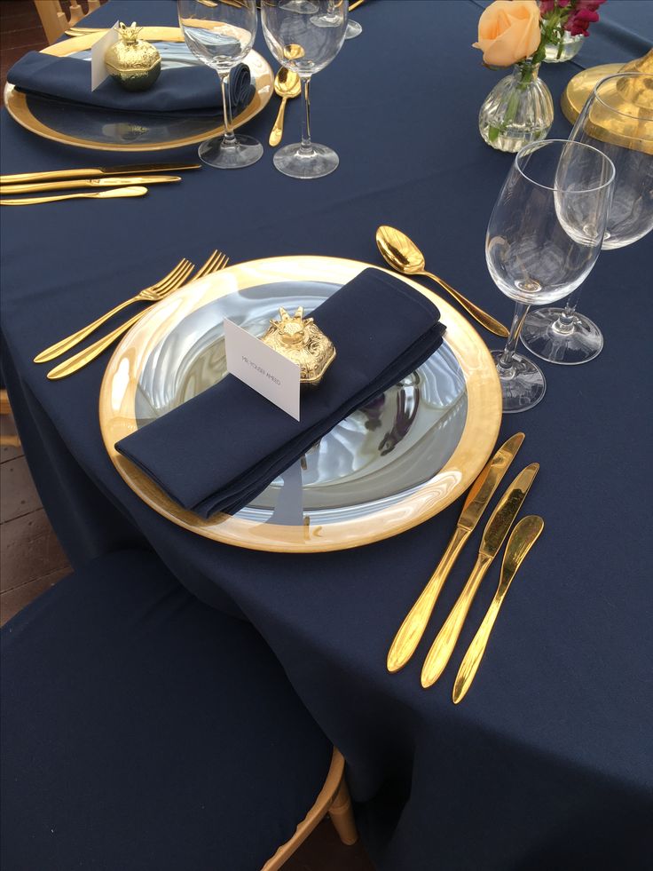 the table is set with gold and black place settings, silverware, and napkins