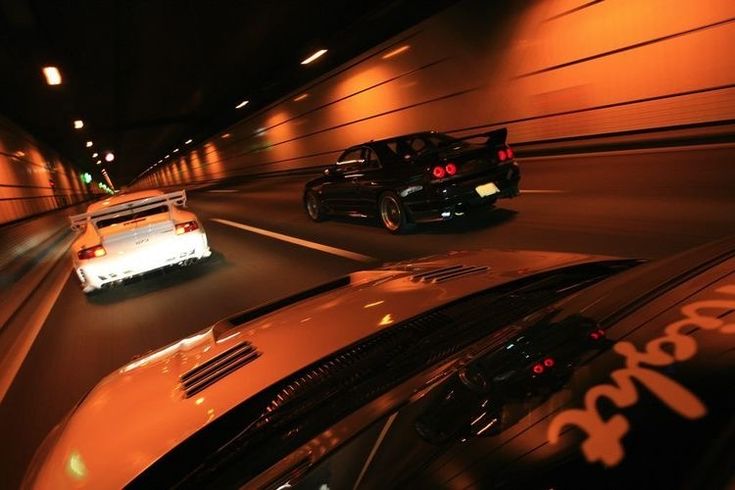 two cars driving down the road at night