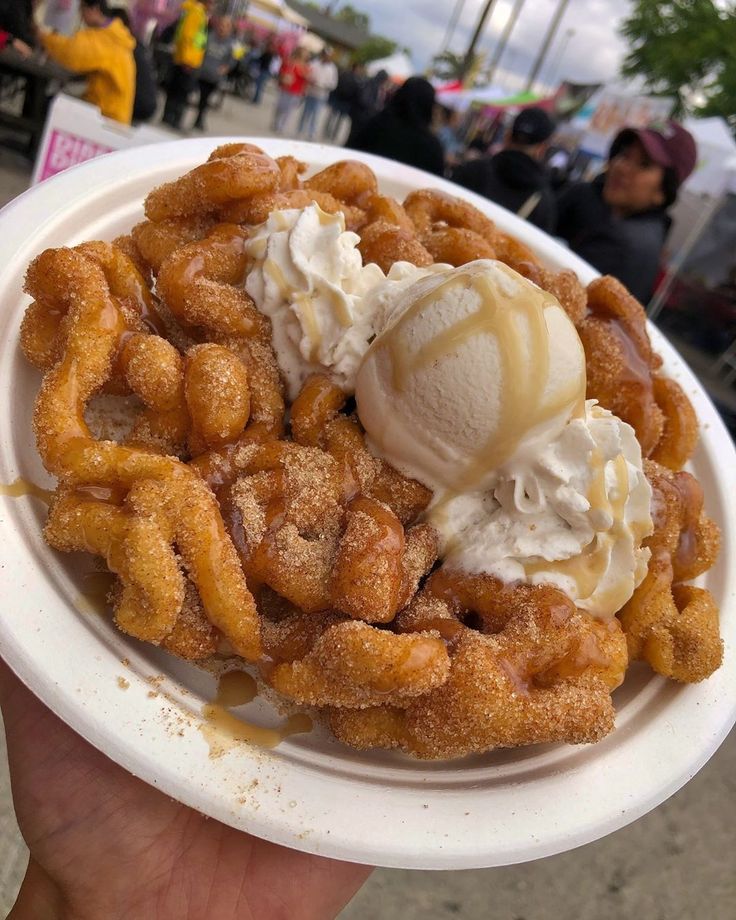 a person holding a white plate with some food on top of it and ice cream in the middle