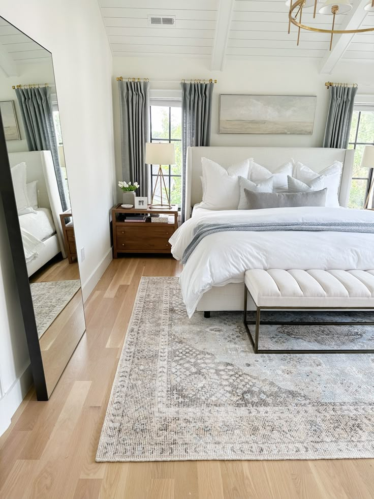 a bed room with a neatly made bed and a large mirror on the wall above it