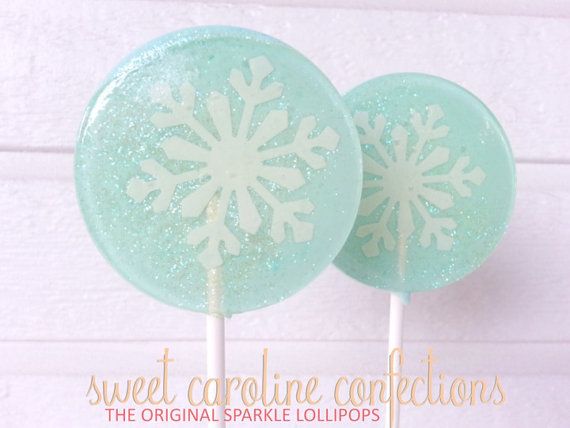 two lollipops with snowflakes on them sitting on top of each other