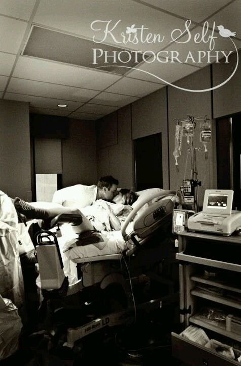 black and white photograph of two people laying in a hospital bed with an iv machine