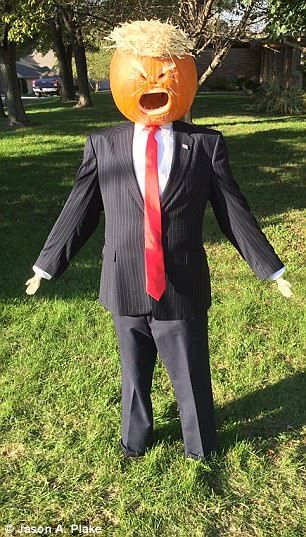 a man wearing a suit and tie with an orange pumpkin head on his head, standing in the grass