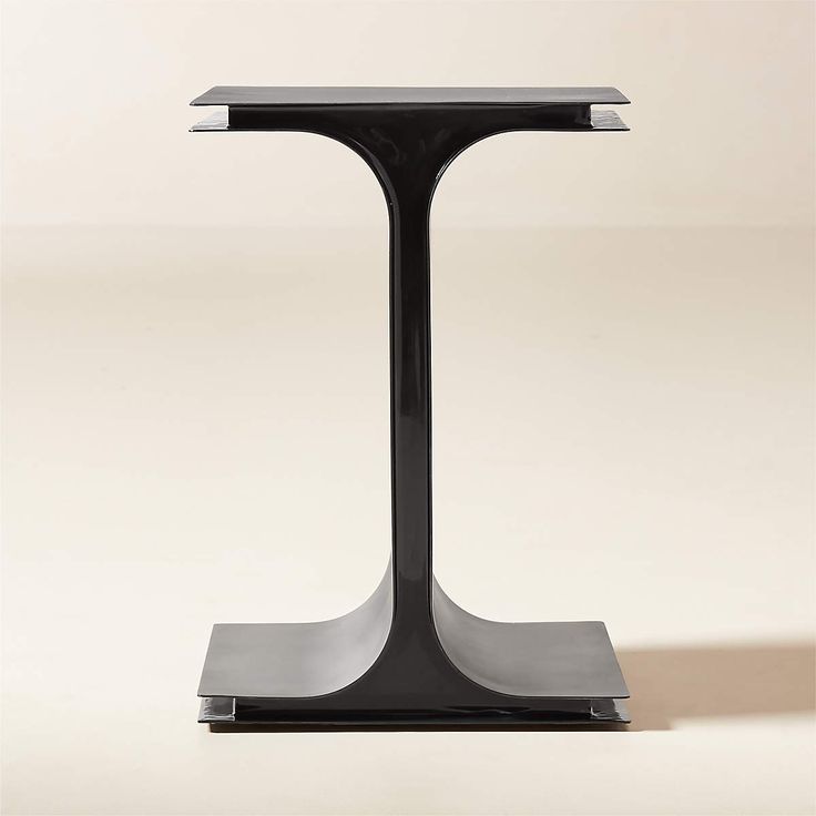 a modern black and silver side table with one leg on the base, in front of a plain white background