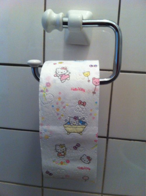 a hello kitty toilet paper roll hanging from a metal holder on a tiled bathroom wall