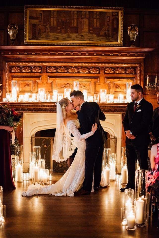 a bride and groom kissing in front of candles