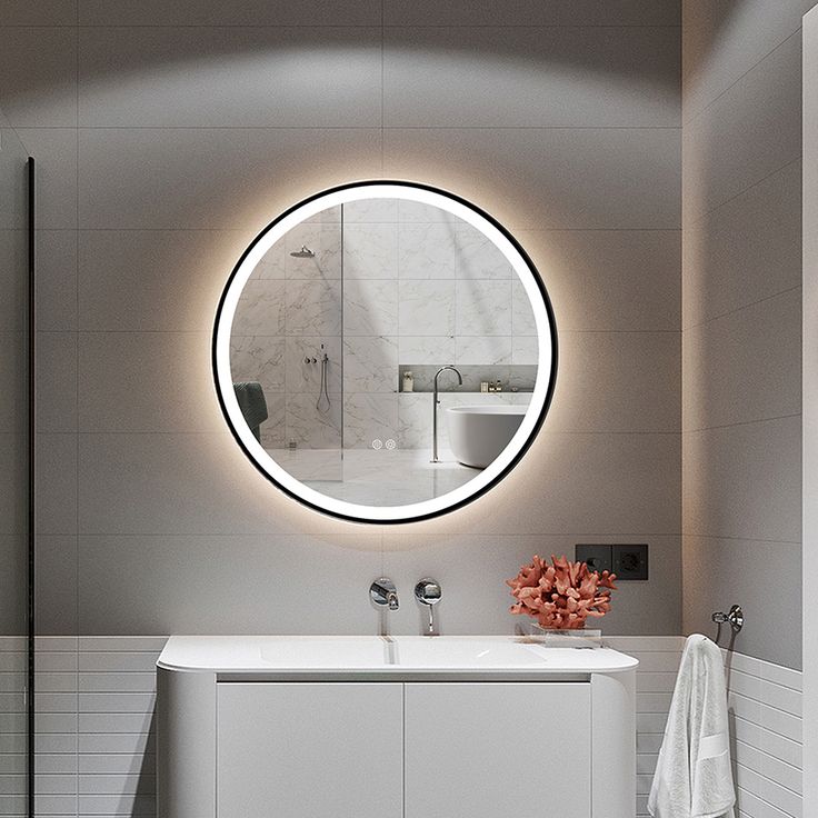 a bathroom with a round mirror above the sink and a white bathtub next to it