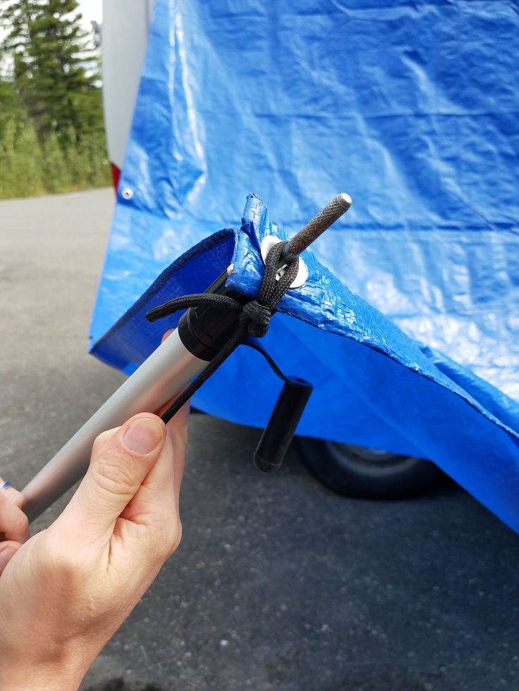 a person holding an umbrella in their hand while standing next to a blue tarp