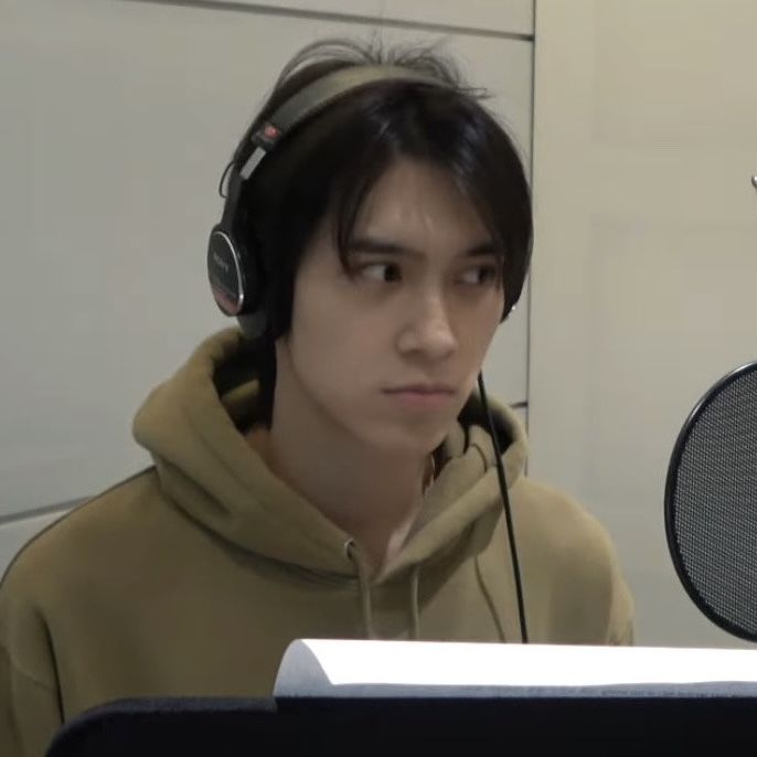 a young man wearing headphones sitting in front of a laptop computer