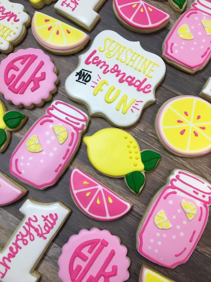 decorated cookies with pink and yellow icing, lemons, and mason jars on a table