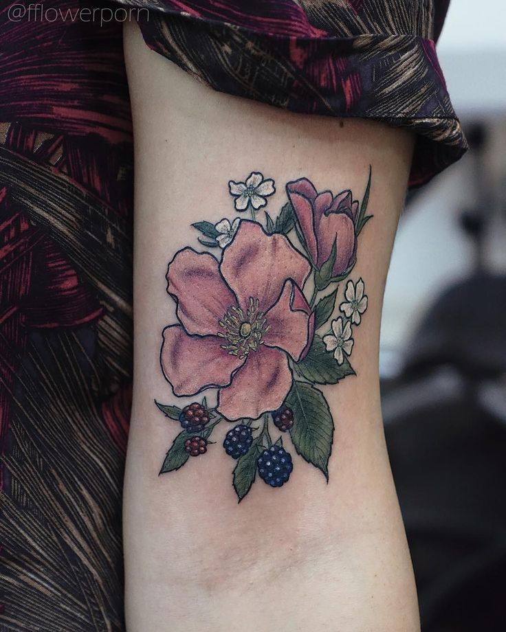 a flower tattoo on the side of a woman's right leg with berries and flowers around it