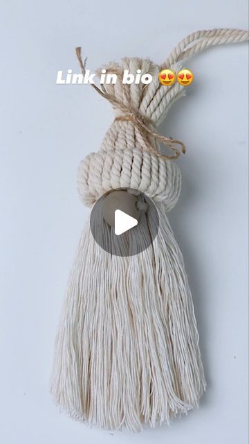 a white tassel hanging from a rope on top of a table with the words link in bio above it