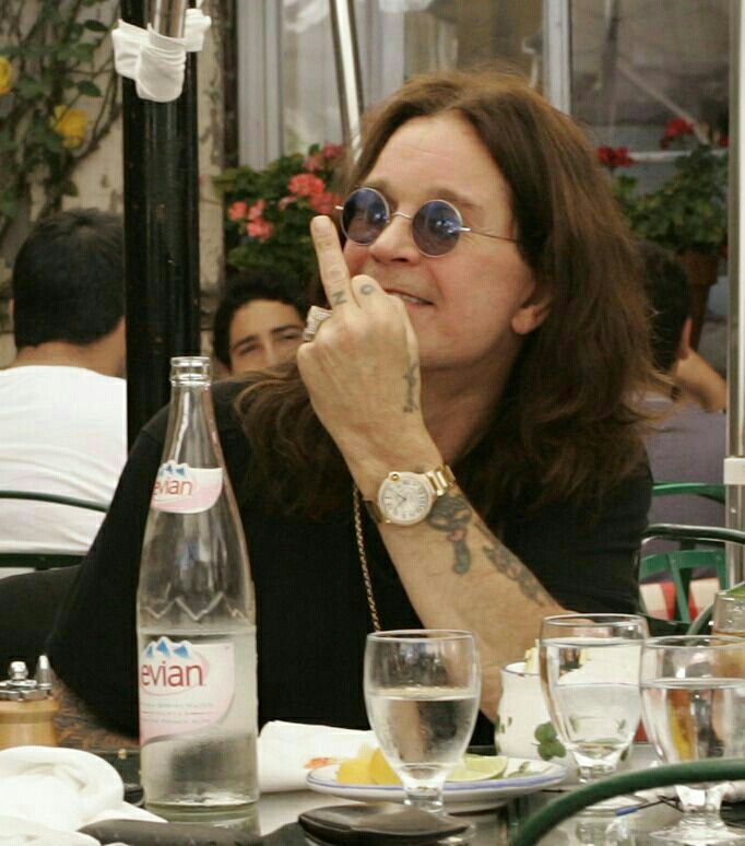 a woman sitting at a table in front of a bottle of water and wine glasses