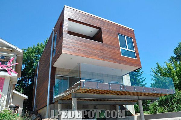 a modern house with wood and glass on the top floor, surrounded by concrete blocks