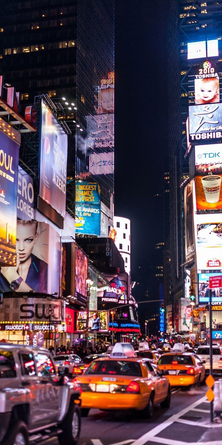 a busy city street at night with lots of neon lights and billboards on the buildings