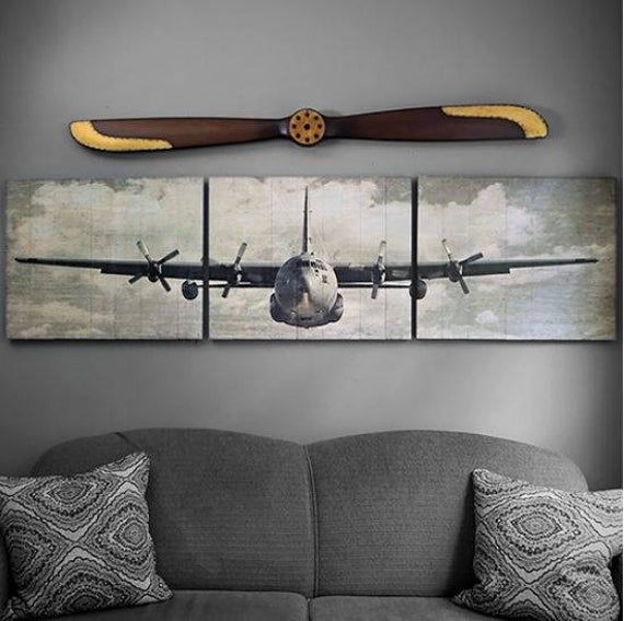 an airplane hanging on the wall above a couch with two pillows and some throw pillows