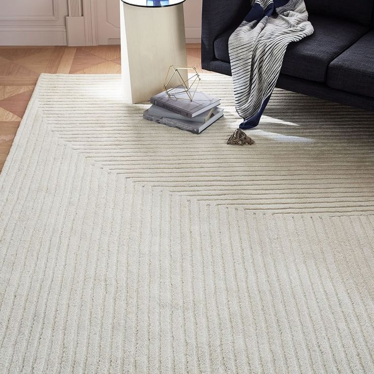 a living room with a black couch and white rugs on the floor next to a lamp