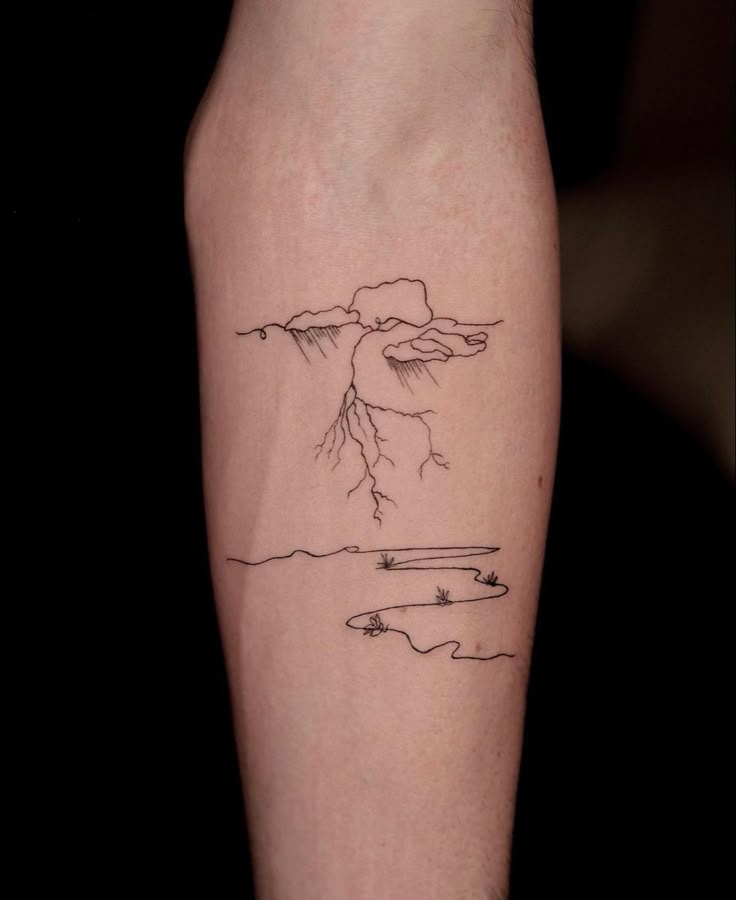 a person with a tattoo on their arm that has a mountain and lake in it