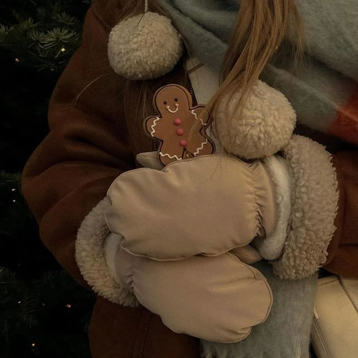 a girl holding a teddy bear wrapped in a blanket with a christmas ornament on it