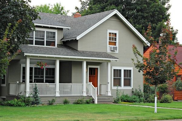 a gray house with white porches and red doors