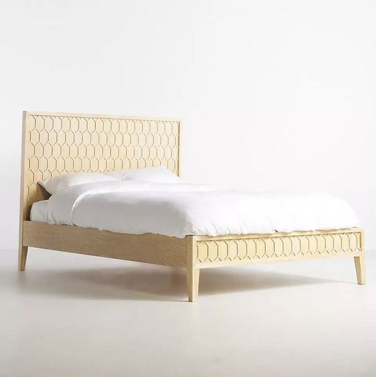 a bed with white sheets and wooden headboard on top of an unfinished bed frame