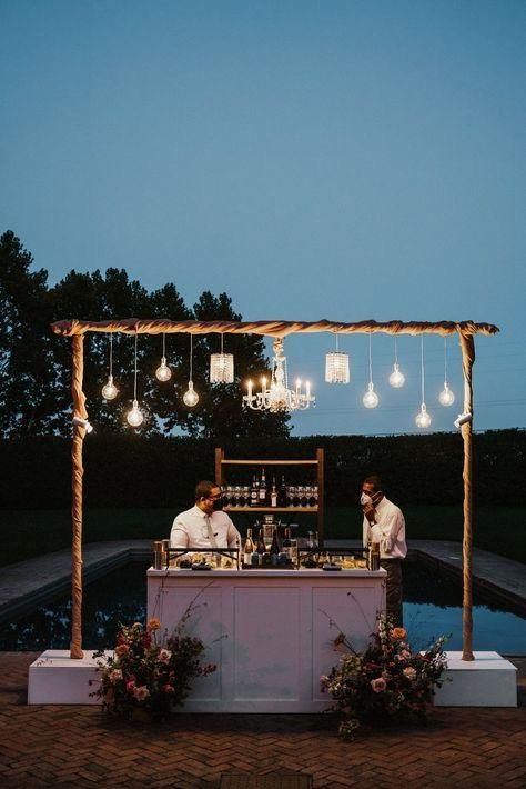 two men standing at a bar with lights hanging from it's ceiling above them