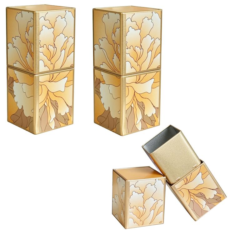 three gold boxes with flowers on them and one has a lighter in the other box