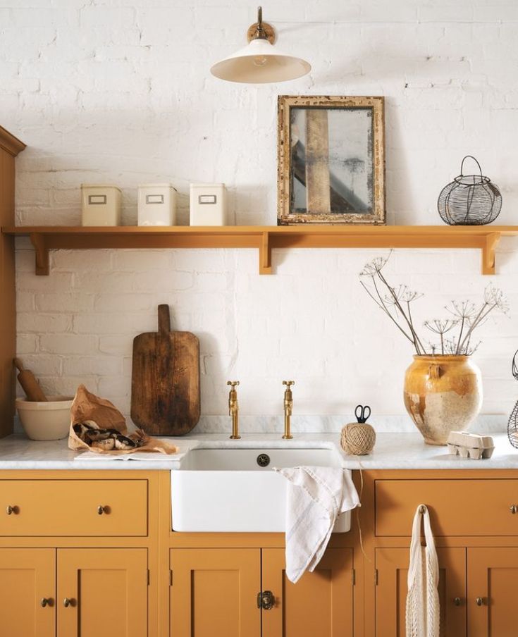 a kitchen with yellow cabinets and white counter tops is pictured in this image, there are various items on the shelves above the sink