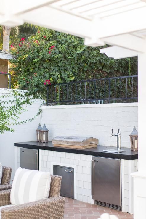 an outdoor kitchen with grill, sink and chairs