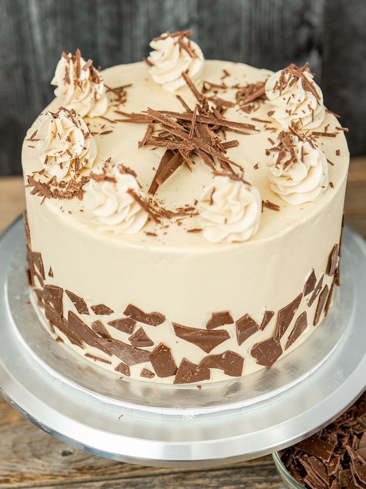 a cake with white frosting and chocolate shavings is on a silver platter