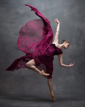 a woman in a purple dress is dancing with her arms spread out and one leg bent