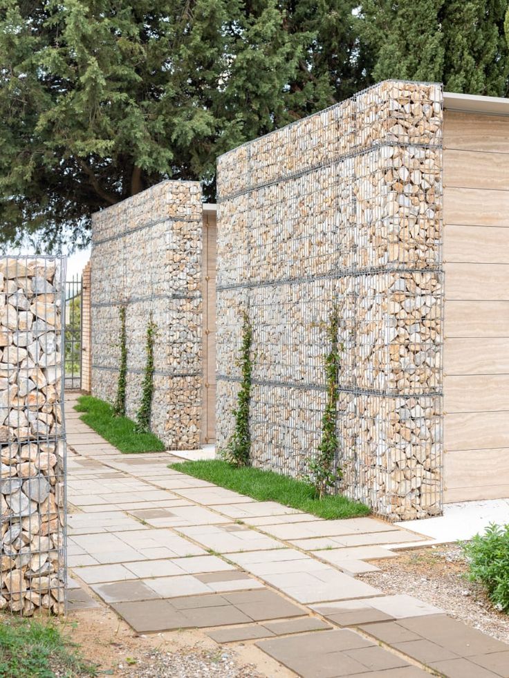 a stone wall and walkway with grass growing between the two walls, along side each other