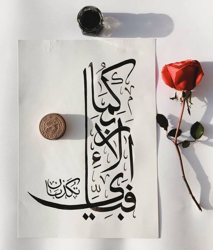 a piece of paper with arabic writing on it next to a rose and a penny