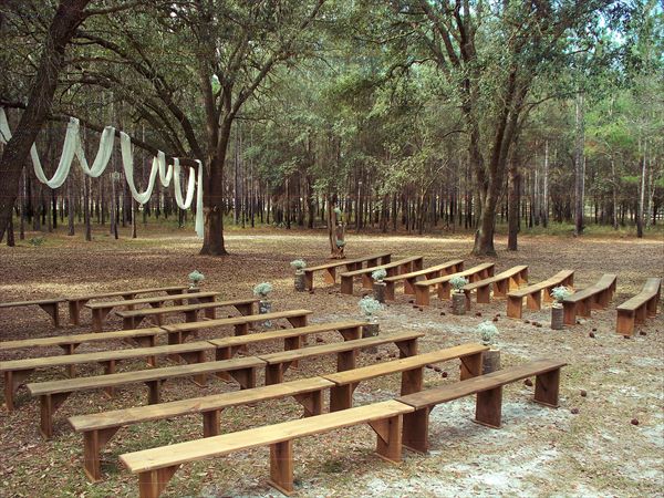 wooden benches are lined up in the middle of a park with bunting strung from trees