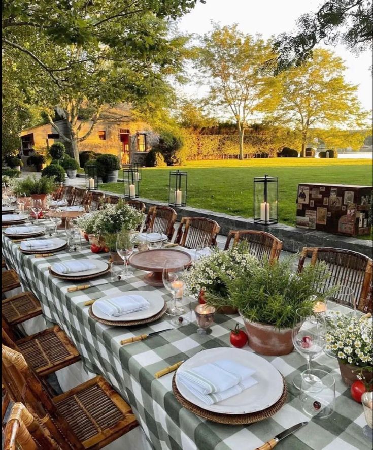 a long table set up with place settings for dinner outside in the evening sun,