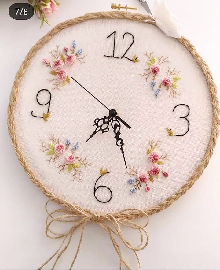 an embroidered clock with flowers on the face and numbers painted on it's sides