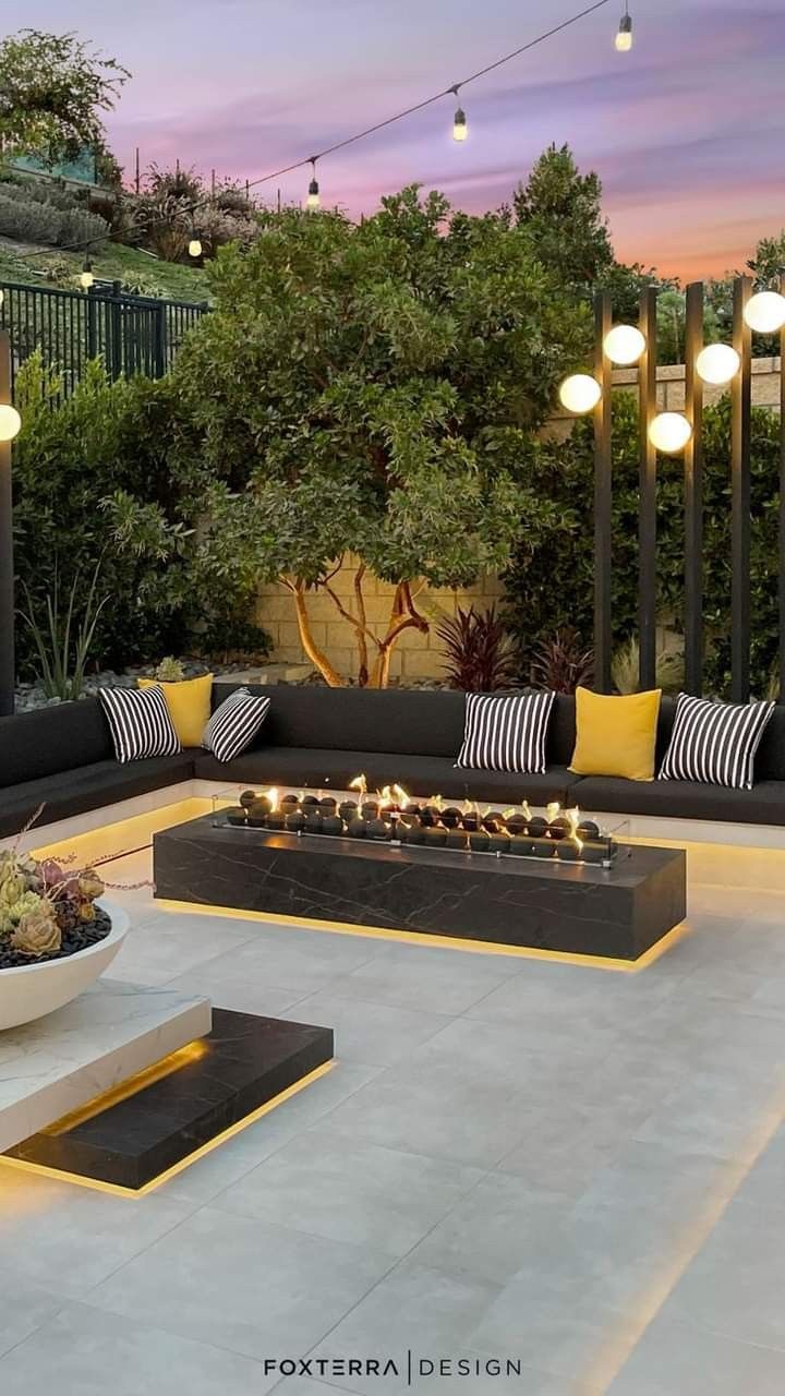 an outdoor living area with couches, tables and lights