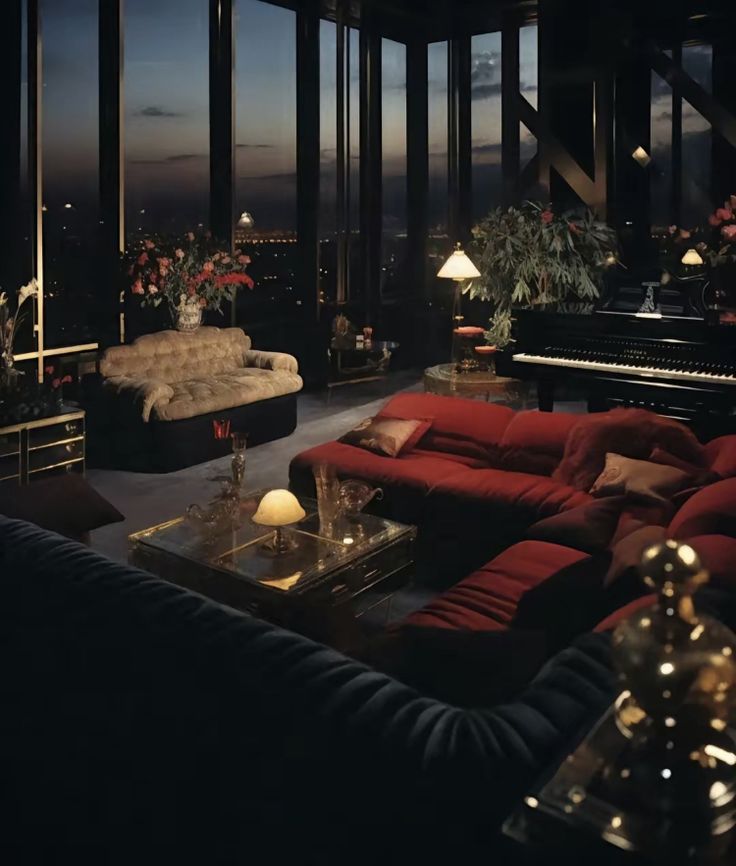 a living room filled with lots of red couches next to a piano and large windows