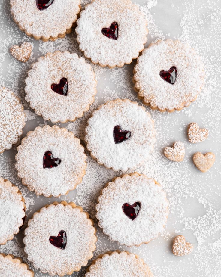 heart shaped cookies with powdered sugar and jelly in the shape of hearts on a table