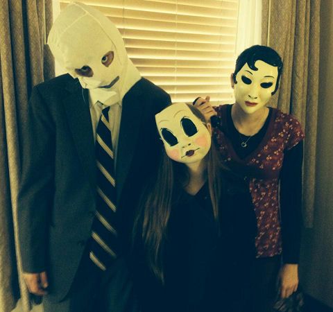 three people wearing masks standing next to each other in front of a window with blinds