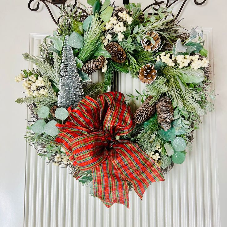 a christmas wreath with pine cones and evergreens