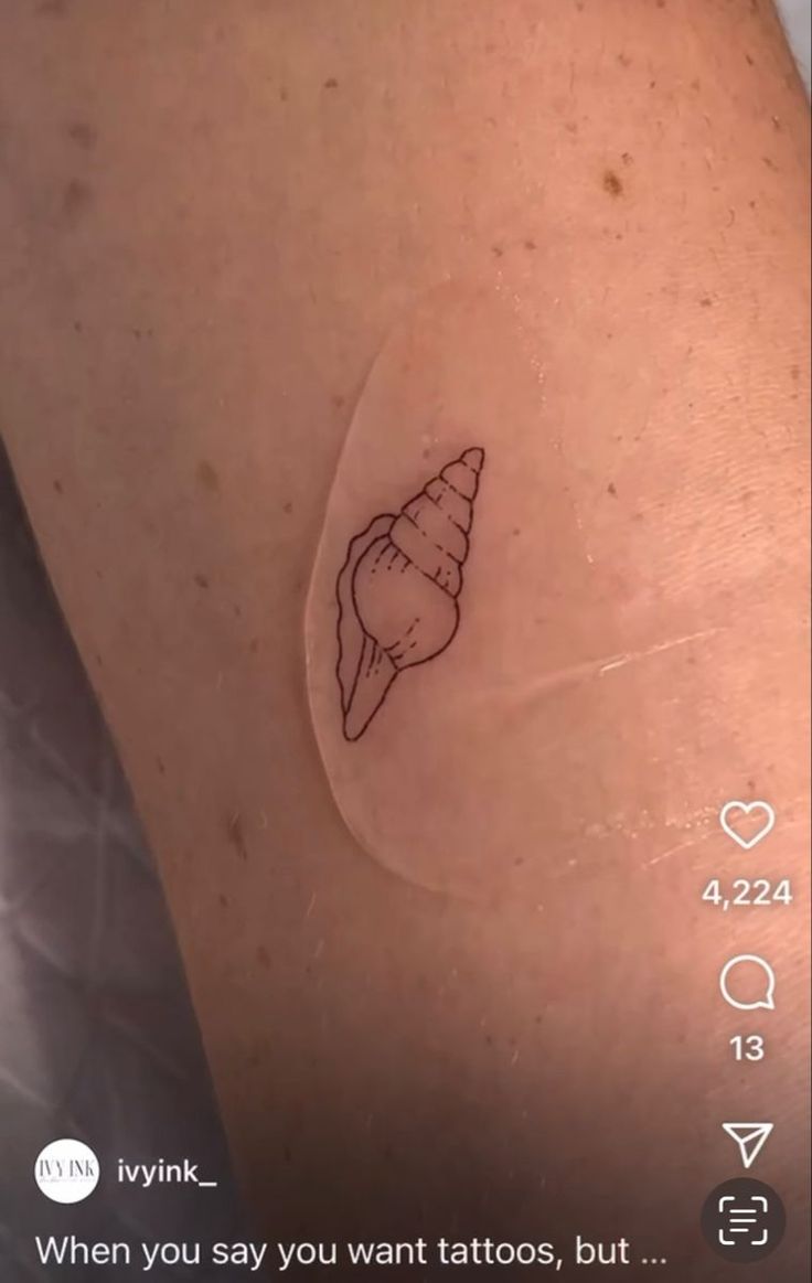 a small tattoo on the back of a woman's left arm, with a sea shell