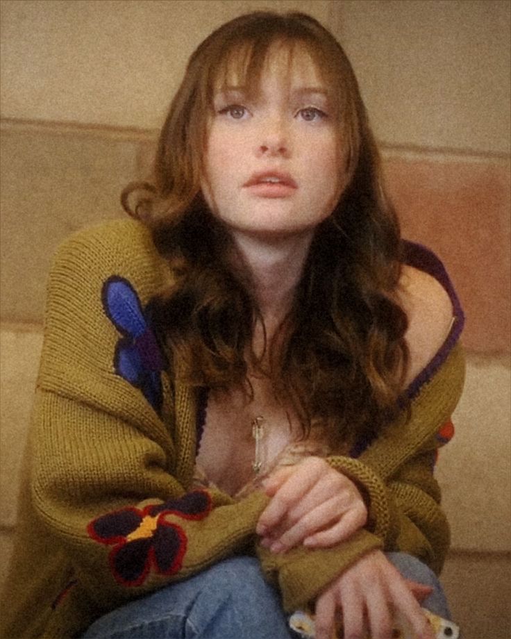 a woman with long hair sitting on the ground