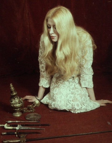 a woman sitting on the floor next to an old clock and other antique items in front of her