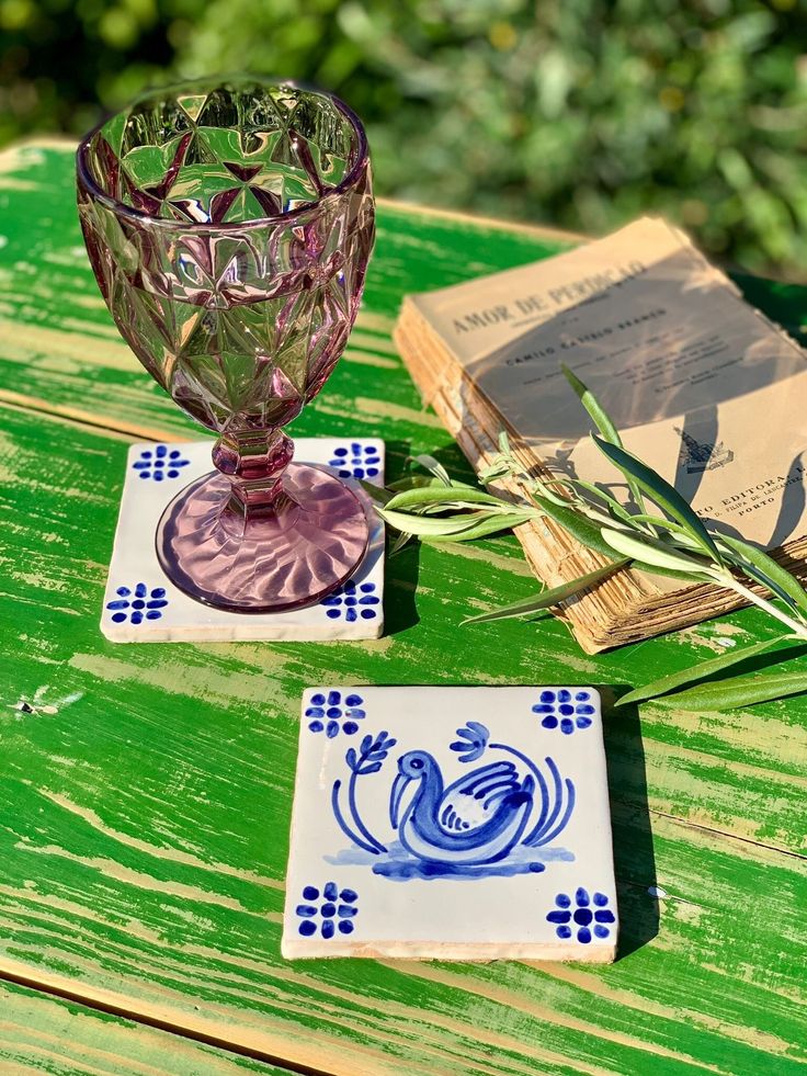 two glass dishes sitting on top of a wooden table next to an open book and plant